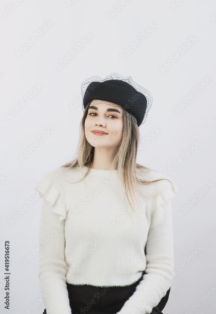 girl in a white sweater posing in a felt hat on a light background girl in a white sweater posing in a felt hat on a light background