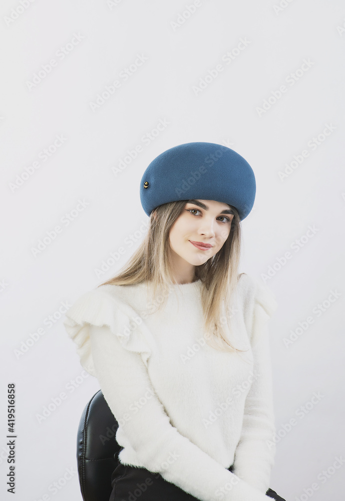 girl in a white sweater posing in a felt hat on a light background girl in a white sweater posing in a felt hat on a light background