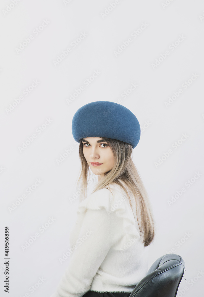 girl in a white sweater posing in a felt hat on a light background girl in a white sweater posing in a felt hat on a light background