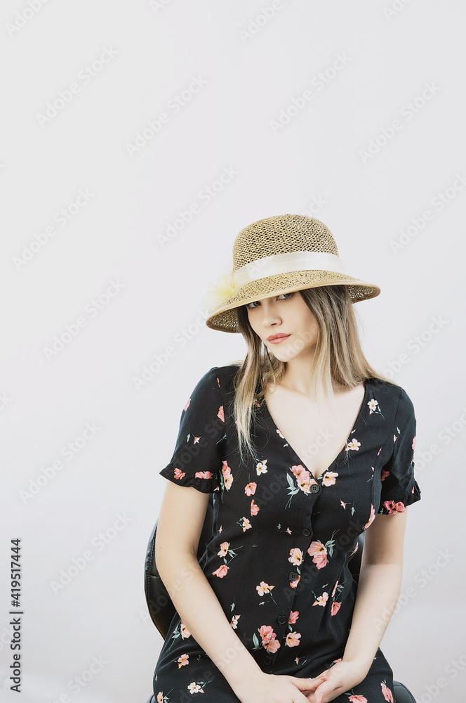 girl in a sundress and straw hat posing on a light, solid background girl in a sundress and straw hat posing on a light, solid background