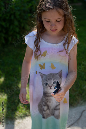 High angle view of girl holding butterfly while standing inher yard photo