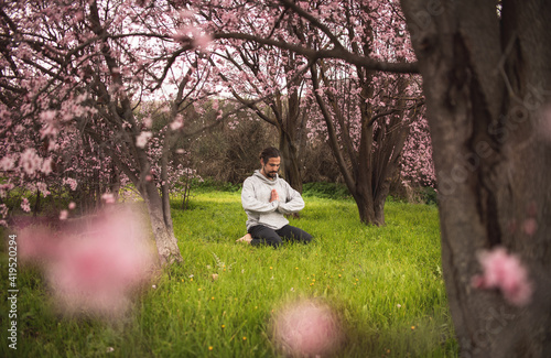 Young man stretching for a yoga session in the park. Fitness, healthy habits and wellness concepts.