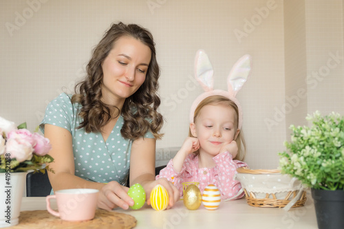 Easter, family, holiday and children concept. Mother and daughter painting eggs. Happy family preparing for Easter