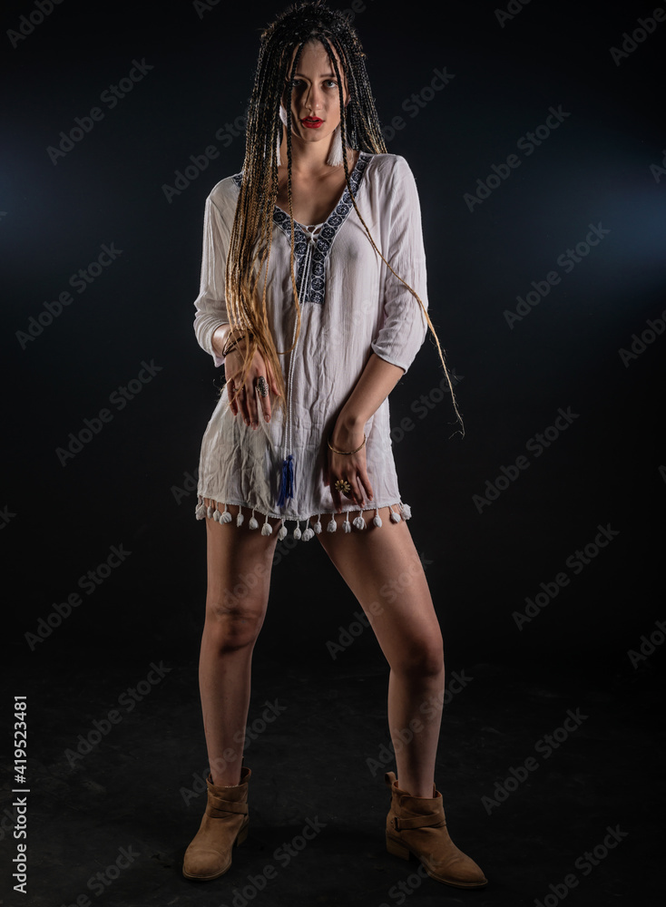  Portrait of a charming girl with braids with a mystic look at the camera. Studio black background..