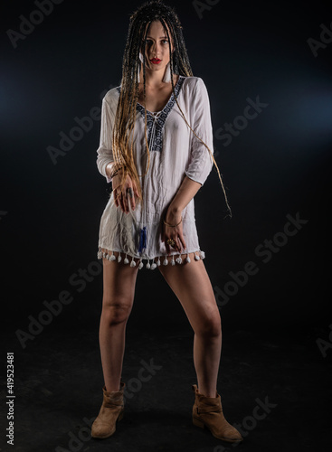  Portrait of a charming girl with braids with a mystic look at the camera. Studio black background..