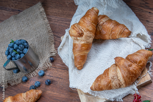 Freshly baked croissants with berries, jam on dark background, selective focus
