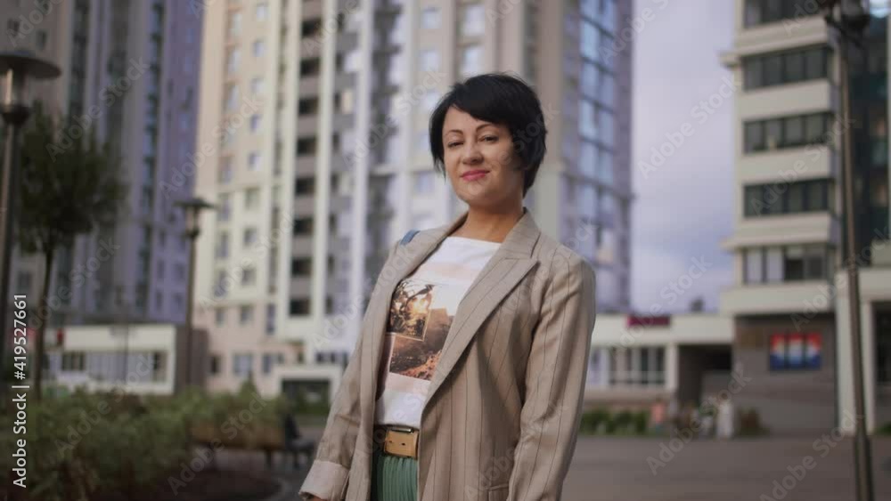 brunette stylish woman stands in the city near houses and smiles brunette stylish woman stands in the city near houses and smiles