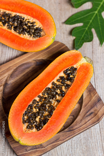 Fresh papaya cut in half on a wooden table
