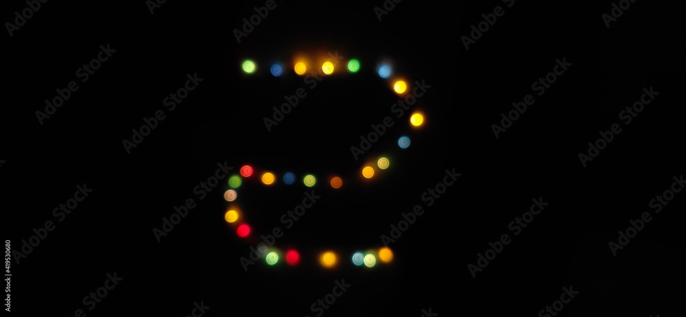 Closeup of Number (2) made with multicolored blurred bokeh Christmas lights in a isolated black background with copy space