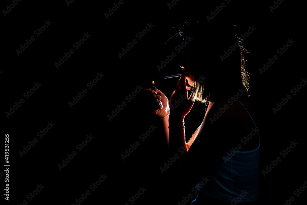 Portrait of smoking young woman on dark background. Cigarette concept. Blue smoke. Horizontal shot. Portrait of smoking young woman on dark background. Cigarette concept. Blue smoke. Horizontal shot.
