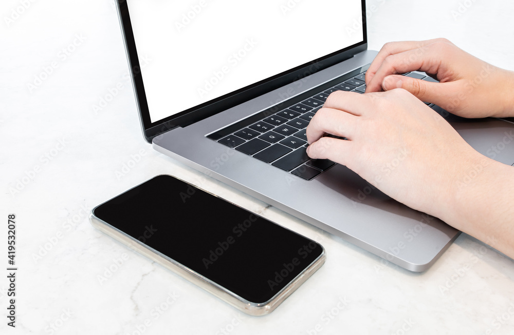 A person typing on keyboard with mobile phone on white marble table, digital portable devices for businessman and student. Concept of people using technology for virtual communication at workplace. A person typing on keyboard with mobile phone on white marble table, digital portable devices for businessman and student. Concept of people using technology for virtual communication at workplace.