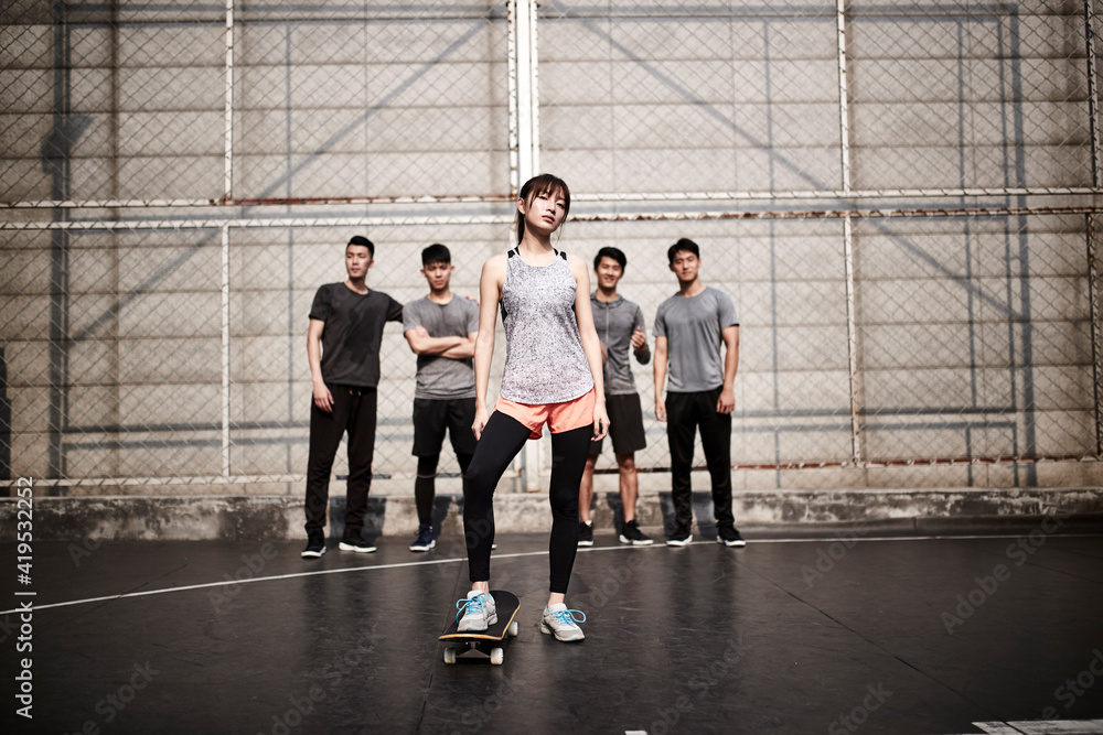 young asian female skateboarder and her male friends