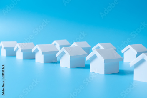 Row of miniature 3D white houses on blue background for real estate property  housing development or community