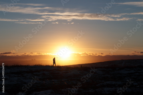 Silhouette of a person walking in a park at sunset