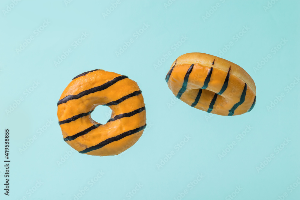 Two flying orange donuts on a blue background.