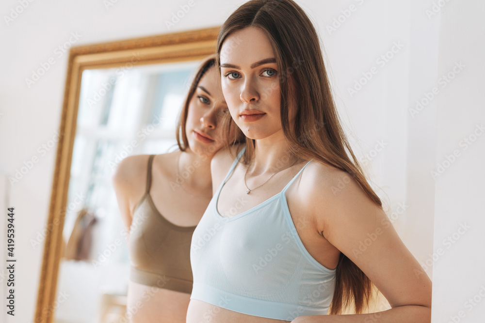 Fashion beauty models two sisters twins beautiful girls with long hair in sport seamless ribbed underwear in the bright studio