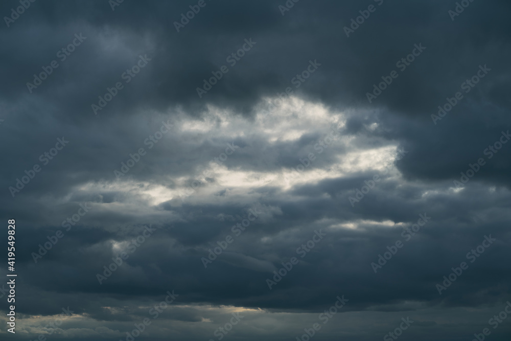 view of the dramatic sunset sky with heavy dark cumulus clouds and natural purple-orange lighting from the evening dawn. picturesque artistic backdrop for atmospheric design. view of the dramatic sunset sky with heavy dark cumulus clouds and natural purple-orange lighting from the evening dawn. picturesque artistic backdrop for atmospheric design.
