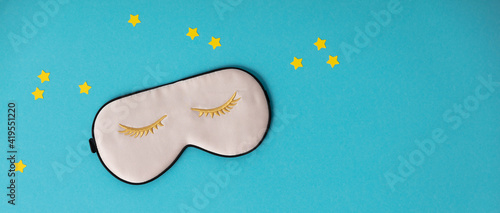 Pink sleeping mask and paper stars on blue background, concept of rest, quality of sleep, good night, insomnia, relaxation