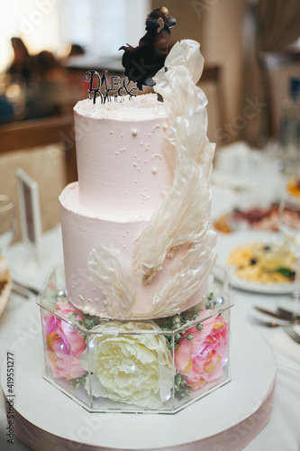 Wedding cake. Confectionery art. Three-tiered wedding cake.Cake with fresh flowers. Cake with lighting. Candy bar.