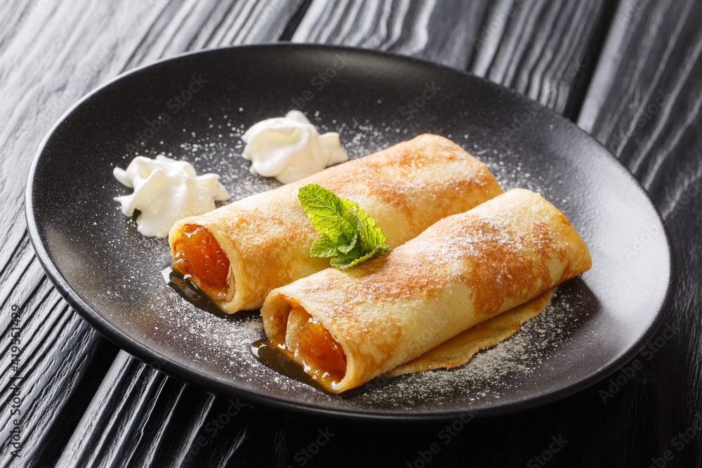 Austrian breakfast Palatschinken Apricot crepes with powdered sugar close-up in a plate on the table. horizontal