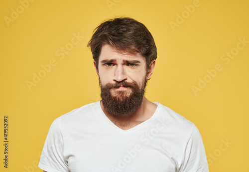 Emotional man on a yellow background in a white t-shirt thick beard brunette model
