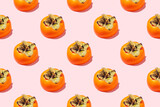 Seamless pattern Half orange persimmons with leaves on a pink background