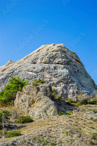 Rock and vegetation are scarce in Crimea against clouds and sky.