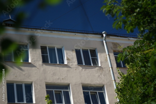 A city wall with windows in a building with apartments for rent. A rainwater downpipe is on the wall outside. High quality photo