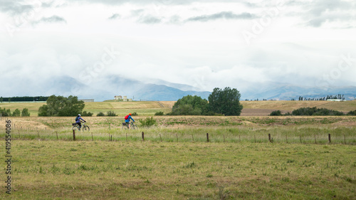 Two cyclists riding the Otago Rail Trail with clouds covering the mountains of picturesque Central Otago © Janice