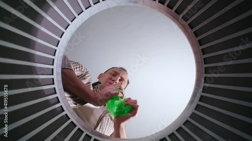 Brunette man throwing plastic bottles, bottom view