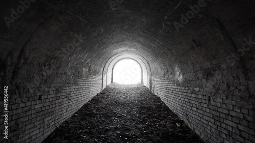Exit from the old abandoned brick arch tunnel of the 19th century fortification with light in the end. Dolling view.