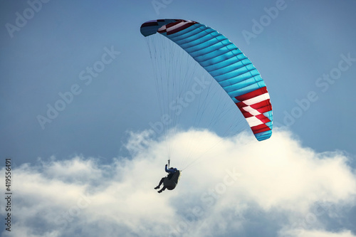 Paraglider flying over the mountains. Active people enjoying in extreme and adrenalin sports.