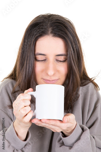 Portrait of a young adorable brown woman enjoying her warm cozy hot drink in big blank white mug
