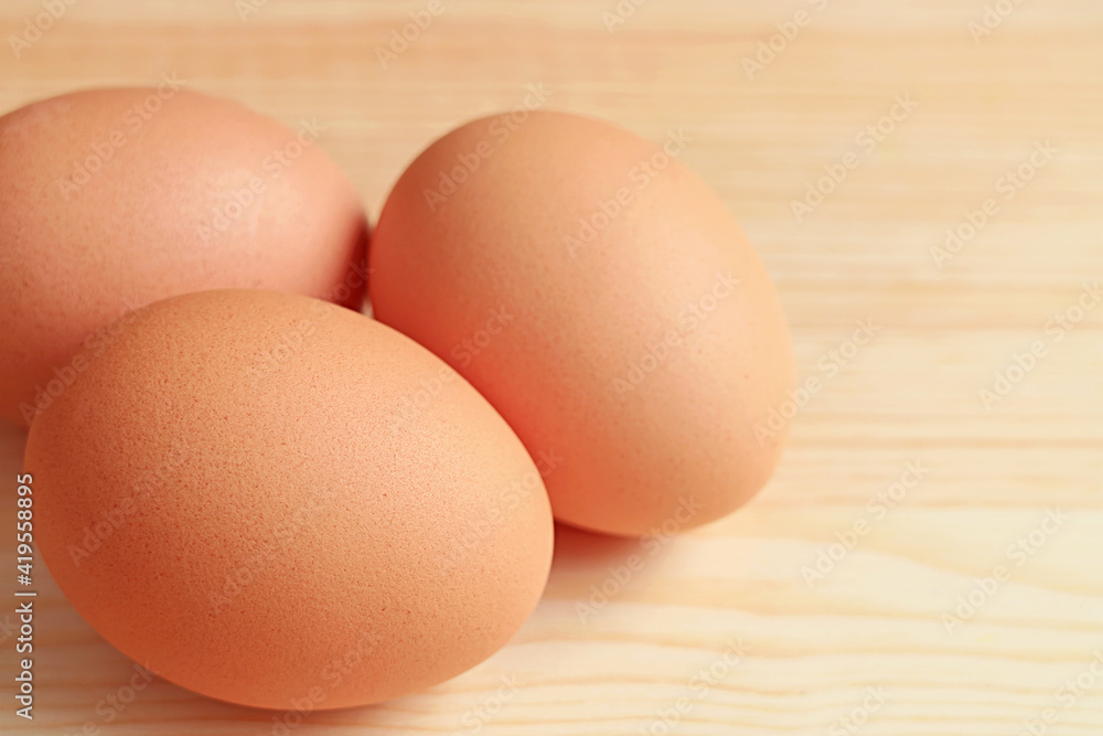 Closeup of Three Chicken Eggs Isolated on Wooden Table with Copy Space Closeup of Three Chicken Eggs Isolated on Wooden Table with Copy Space