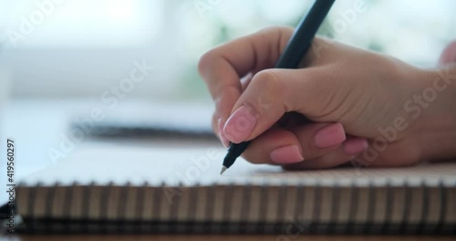 Woman writing in notepad at home photo