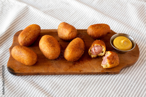 Homemade Mini Corn Dogs on a rustic wooden board, low angle view.
