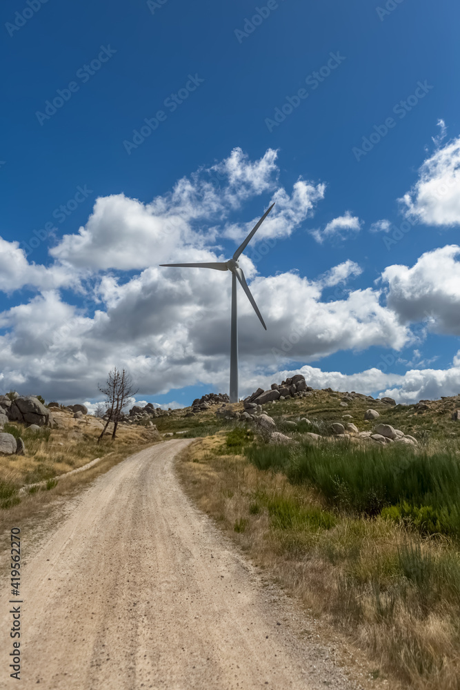 View of a wind turbine on top of mountains, cloudy sky as background