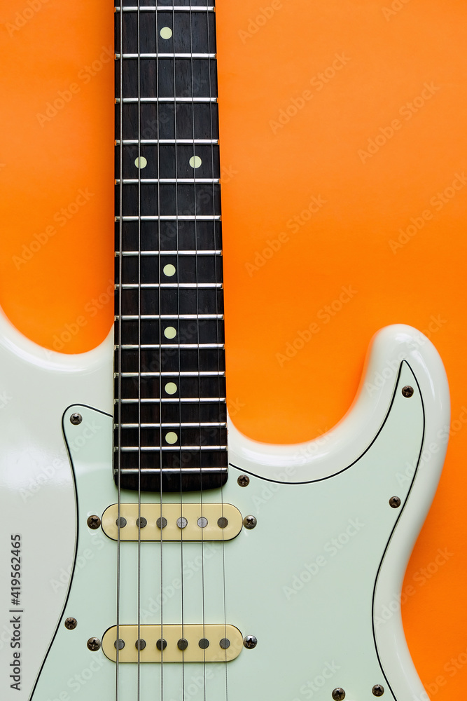 Obraz premium Detail of White Electric Guitar on a orange background.