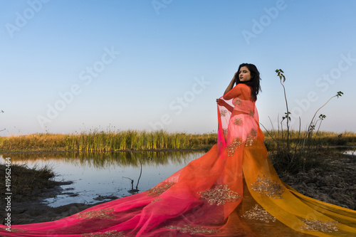 Portrait of beautiful Indian girl wearing Indian traditional dress. Young woman in traditional Indian costume lehenga choli with fashionable hairstyle poses photo