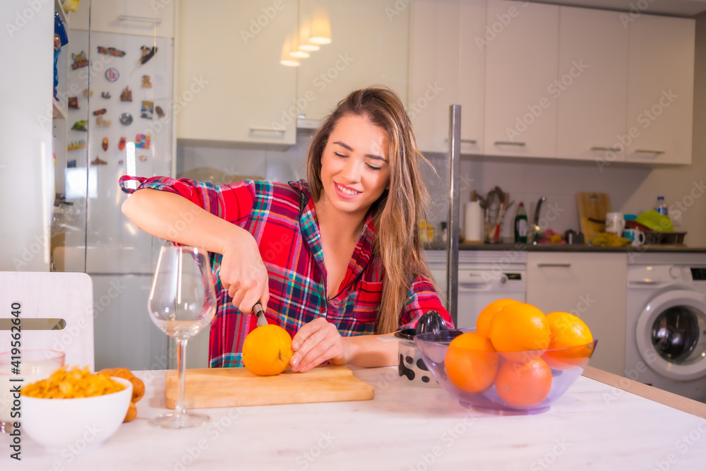Blond Caucasian woman having a fresh orange juice for breakfast in her kitchen