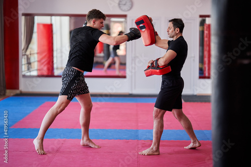 Kickboxing fighter hitting pads with trainer © Xalanx