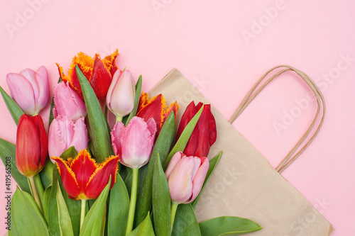 Fototapeta Naklejka Na Ścianę i Meble -  Pink and red tulips and a paper bag on a pink background.