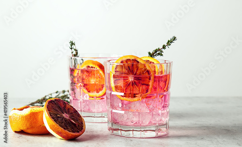 Pink gin cocktail with red blood orange and ice. An alcoholic, refreshing drink.