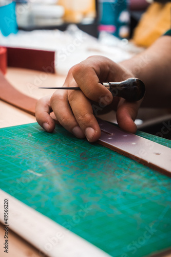 The leather master's hands measure the leather stencil of the belt