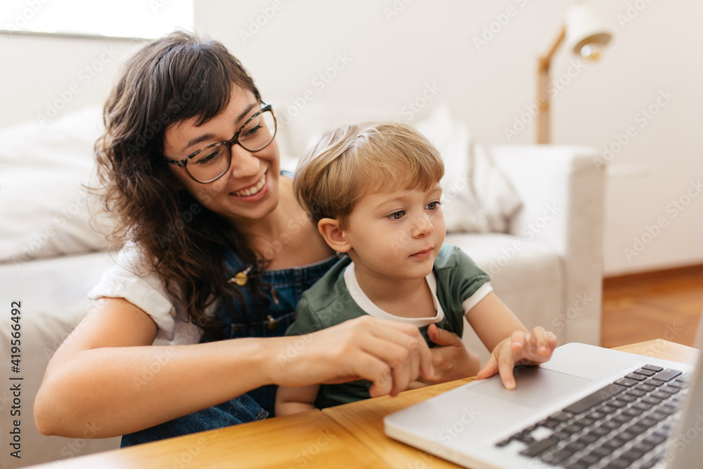 Mãe autônoma e filho sorrindo trabalhando no computador em casa Mãe autônoma e filho sorrindo trabalhando no computador em casa