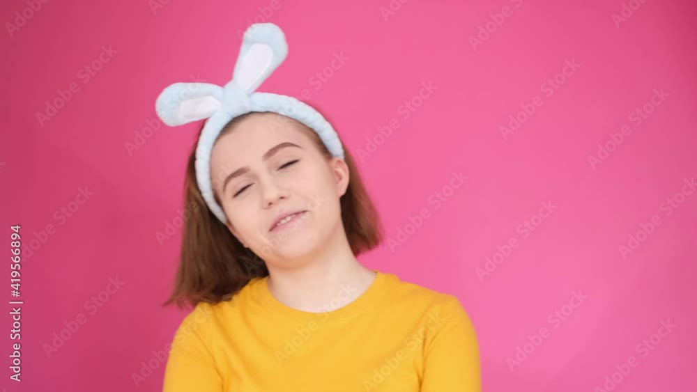 close up portrait of a Caucasian smiling young woman a girl with blue rabbit ears on her head laughing and having fun close up portrait of a Caucasian smiling young woman a girl with blue rabbit ears on her head laughing and having fun