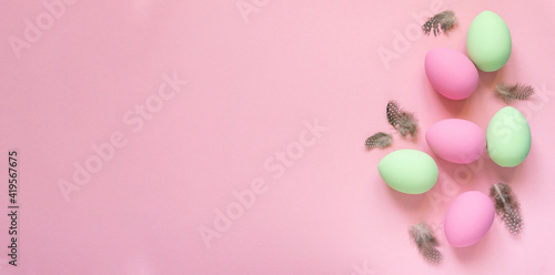 Pink and green easter eggs with feathers on pastel background, space for text photo
