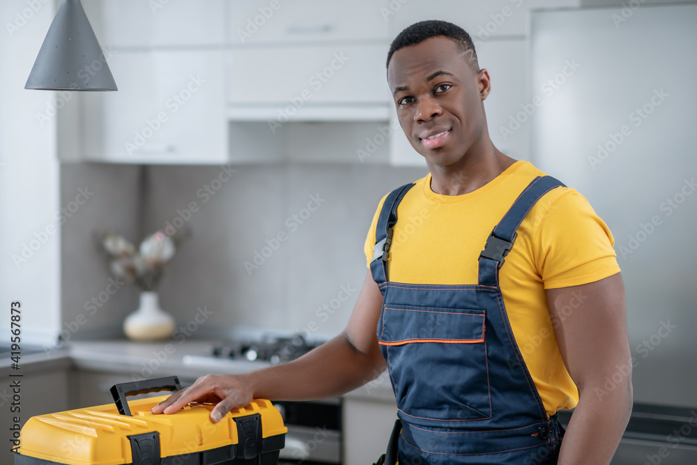 Dark-skinned service man standing in the kitchen Dark-skinned service man standing in the kitchen