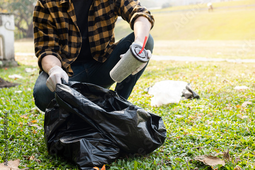 Man's hands pick up plastic bottles, put garbage in black garbage bags to clean up at parks, avoid pollution, be friendly to the environment and ecosystem