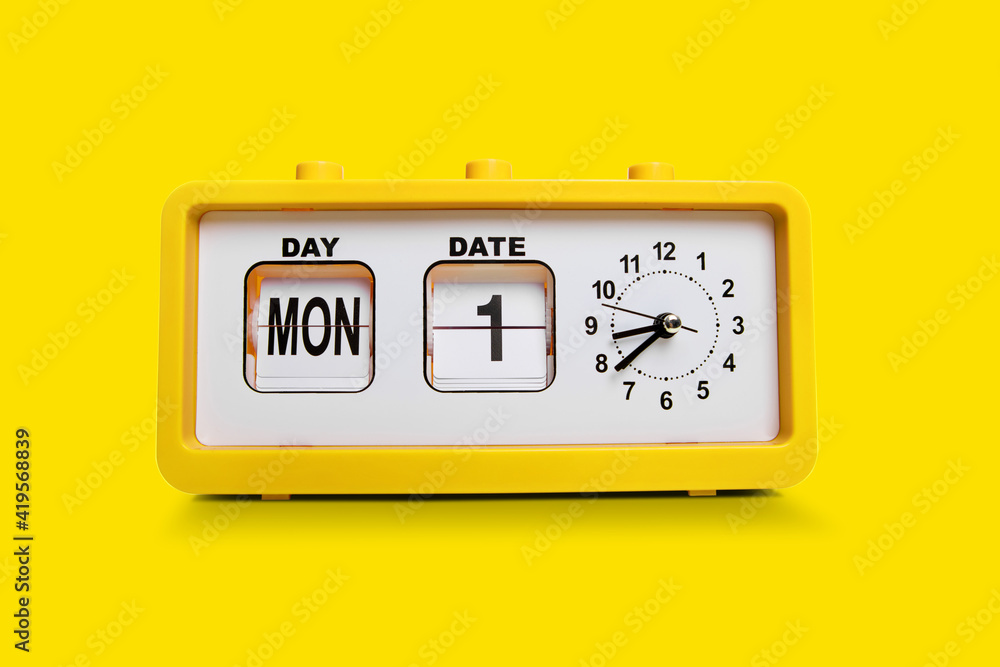 Electronic alarm clock and analog flip calendar. Retro design from 60s 70s home interior. Bright yellow color. Electronic alarm clock and analog flip calendar. Retro design from 60s 70s home interior. Bright yellow color.